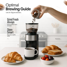 Person pouring coffee beans into a grinder with a cup of coffee and pastries on a table.